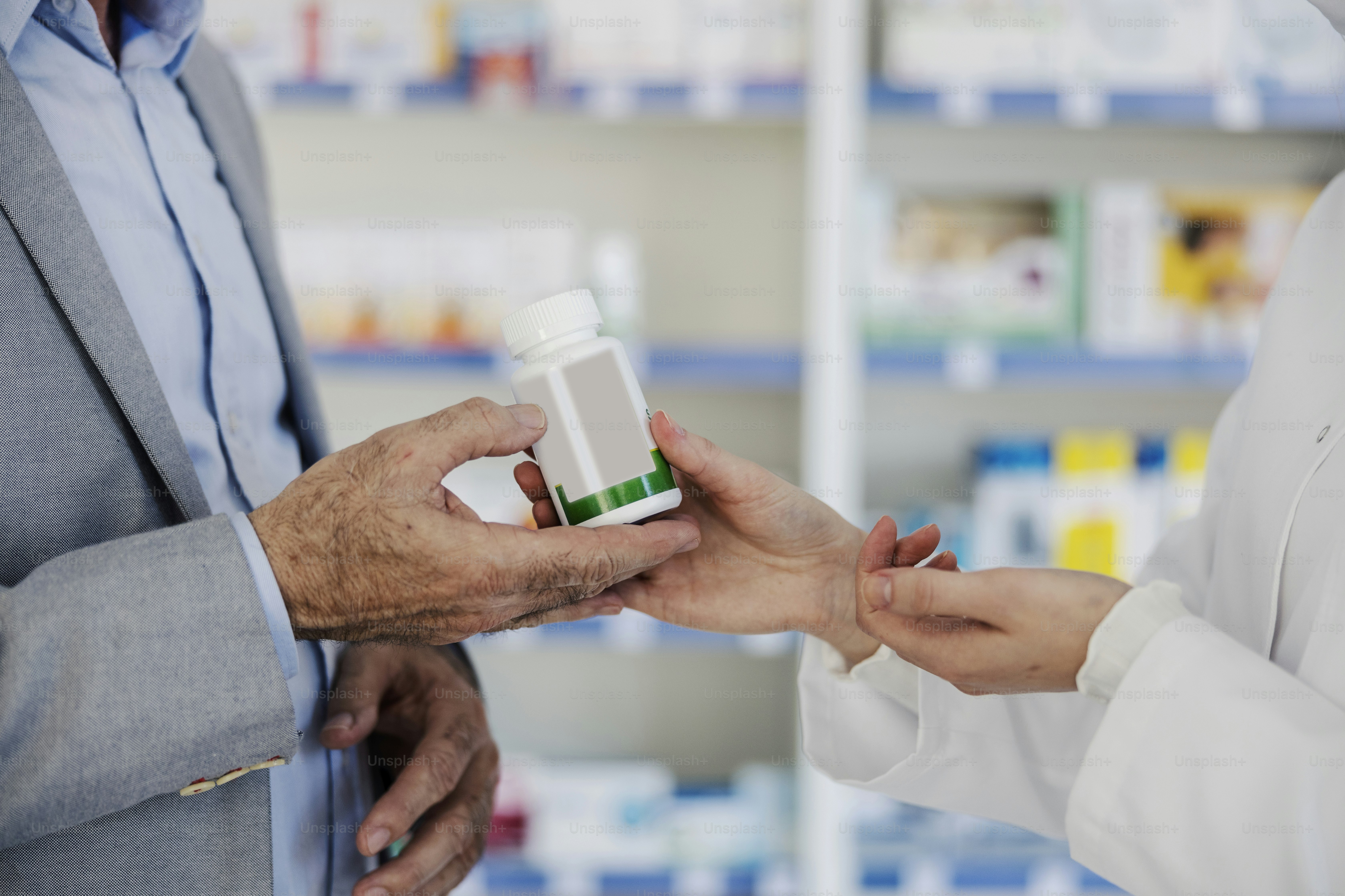 Pharmacist's hands giving bottle with cure to a patient at pharmacy